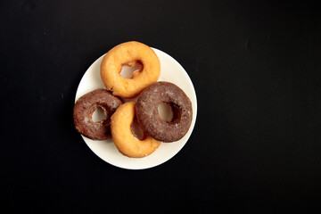 Donuts with high calories and plenty of sugar in the plate on the table