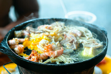 Shrimp on hot black pan with oil and butter to cook grilled bbq on a hot stove. Holiday eating at a restaurant.