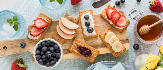 Fototapeta na wymiar A wooden board of breakfast crackers topped with spreads and fresh toppings.