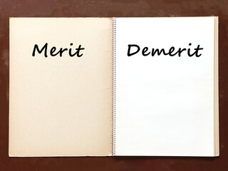 机の上で開いた古いスケッチブックにMeritとDemeritの文字