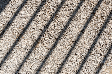 Oblique shadows from the grate on the gravel