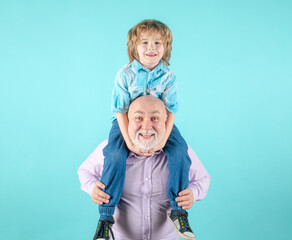Grandfather and grandson piggyback ride with funny face isolated on blue in studio.
