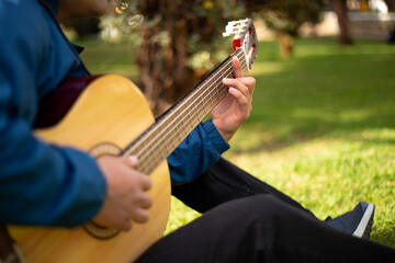 Detalle de joven cantando y tocando guitarra en un parque al atardecer. Concepto de personas y...