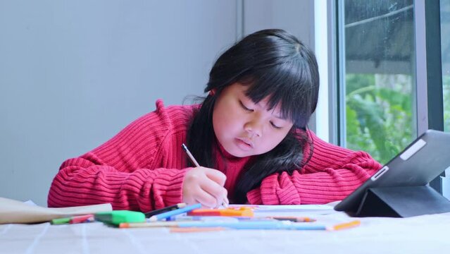 Asian girl sitting at home coloring pictures.