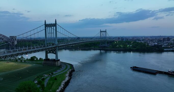 Ferry boat floating by East River. Beautiful Triborough Bridge with transport going by and under it. Evening time in New York.