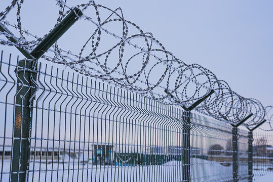 Fence with barbed wire covered with snow in the evening.