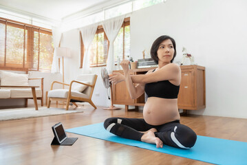 Fototapeta na wymiar Asian Pregnant woman stretching her arms before yoga exercise at home. Expectant female, healthy pregnancy