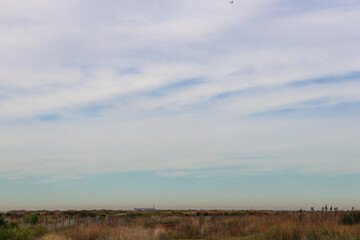 clouds in the sky over coastal landscape with container ship on the sea