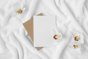 Orchid flowers and paper blank on a white terry towel. Spa mockup with copy space.