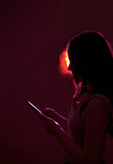 Woman in neon light scrolling smartphone gadget. Futuristic, social media consumption, digital detox concept.
