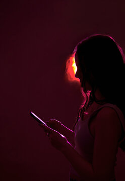 Woman In Neon Light Scrolling Smartphone Gadget. Futuristic, Social Media Consumption, Digital Detox Concept.