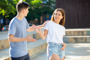 Young man is pestering teenage girl on the street