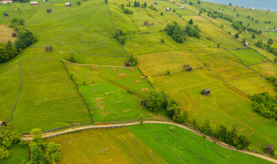 Authentic rural landscape in Romania, in Maramures and Bucovina area. Aerial view with agriculture fields, old houses and cottage on hills during a beautiful summer morning. Travel to Romania.