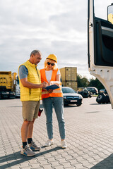 Mature woman and man at cargo warehouse, truck drivers delivery inspection 