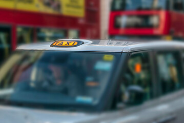 Taxi sign lit in traffic at night.