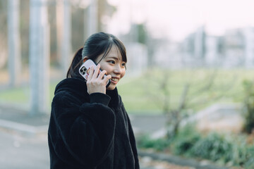 愛知県名古屋市の鶴舞公園をスマートフォンで通話をしている若い女性...