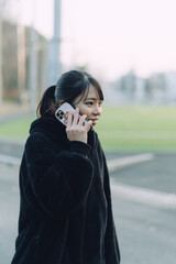 愛知県名古屋市の鶴舞公園をスマートフォンで通話をしている若い女性...