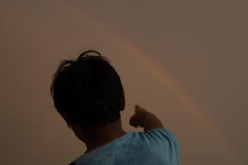 Portrait of a young Indian kid pointing his finger at the rainbow. Happy kid points his finger...