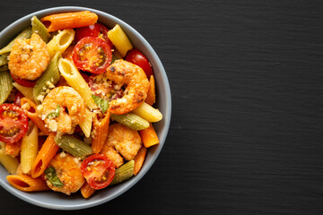 Homemade Tri-Color Penne Salad with Shrimp, Tomato and Basil Bread Crumbs in a Bowl on a black...