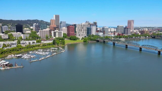 Aerial drone video. of the Portland, Oregon business district slowly pulling away to the larger cityscape including the Willamette River, several bridges with crossing cars and trucks