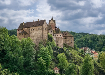 The Romanesque-Gothic stone castle Loket in the Czech Republic on a high green mountain is loved by...