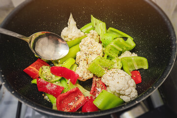 cauliflower, pepper and other vegetables in a frying pan are ready for frying or stewing on the stove
