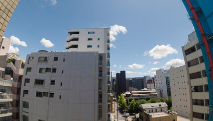 広角レンズで撮影した都市のマンションの様子と青空の風景