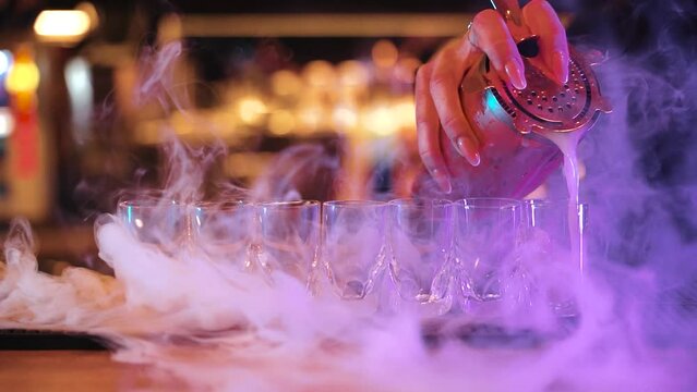 bartender filling up shot glasses with alcoholic drinks (slow motion)