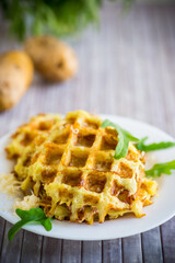 fried potato waffles with cheese in a plate on wooden table.