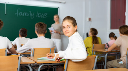 Teenage girl turned around and looking at camera during lesson in classroom.