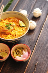 Khao Soi Recipe,Khao Soi,Khao Soi Kai, Thai Noodles Khao Soi, Chicken Curry with seasoning served on black wooden table with decorative leaves, vertical photo.