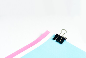 An image isolated binder clip black color stationery paper with a color paper stack for office paperclip on the white background with copy space for text.