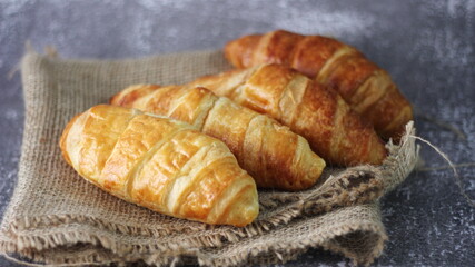 Croissant bread stacked on the table with wooden plates and sackcloth.