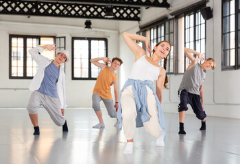 Teenage girl and boys having dance training in studio, performing hip hop elements
