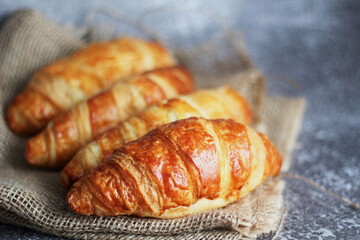 Croissant bread stacked on the table with wooden plates and sackcloth.