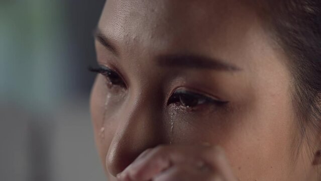 Frustrated and depressed young Asian woman is crying tears coming from her eyes, sad Asian female feel down thinking about problems.