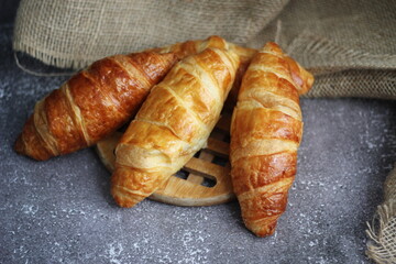 Croissant bread stacked on the table with wooden plates and sackcloth.