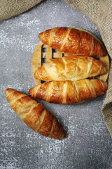 Croissant bread stacked on the table with wooden plates and sackcloth.