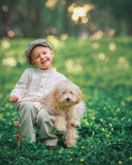 Young boy kid and his dog poodle on the grass together. Happy child hugging his pet smiling with his eyes closed.