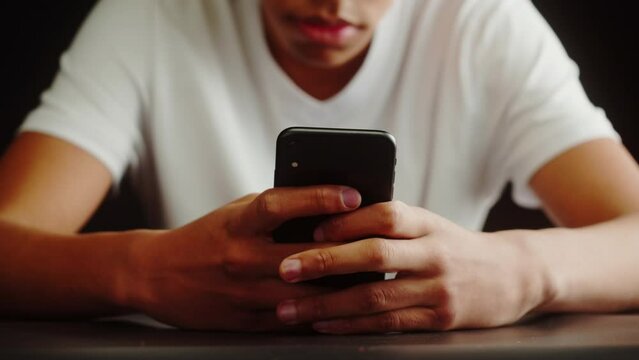 African American Man Using Smartphone. Young Guy Texting At Phone, Teenager Relaxing At Home. Communicating With Family And Friends Online, Sitting On Sofa In Living Room.