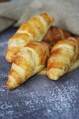 Croissant bread stacked on the table with wooden plates and sackcloth.