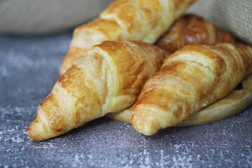 Croissant bread stacked on the table with wooden plates and sackcloth.