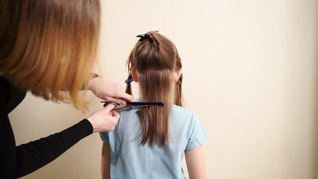 Mom combs her daughter's wet hair and cuts. cutting hair at home. life hacks and rules of hair care. special combs and scissors for hairdressers.