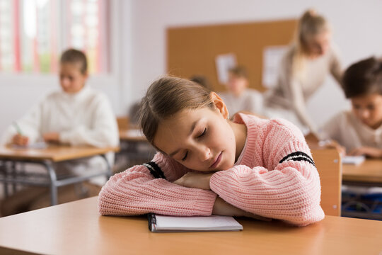 Tired bored teenage schoolgirl sleeping at desk