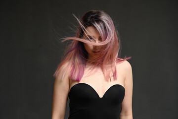 Fototapeta premium Model's hair blowing in the wind. Portrait on a gray background