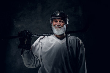 Studio portrait of glad elderly sportsman dressed in protective sportswear against dark background.