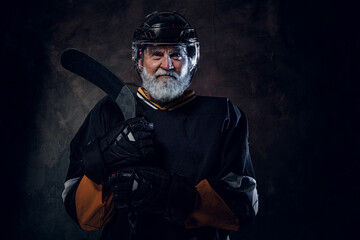 Shot of active senior man hockey player dressed in protective sportswear holding hockey stick.