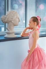 Girl ballerina in a tutu by the window