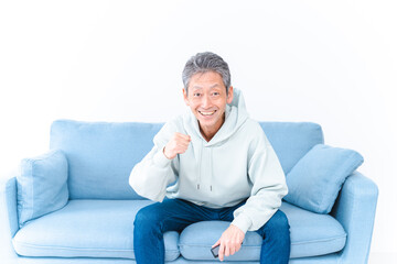 Fototapeta premium 自宅のテレビでスポーツ観戦をする高齢の男性