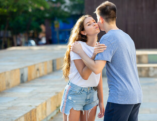 Kiss on cheek of boy and girl on the street of summer city